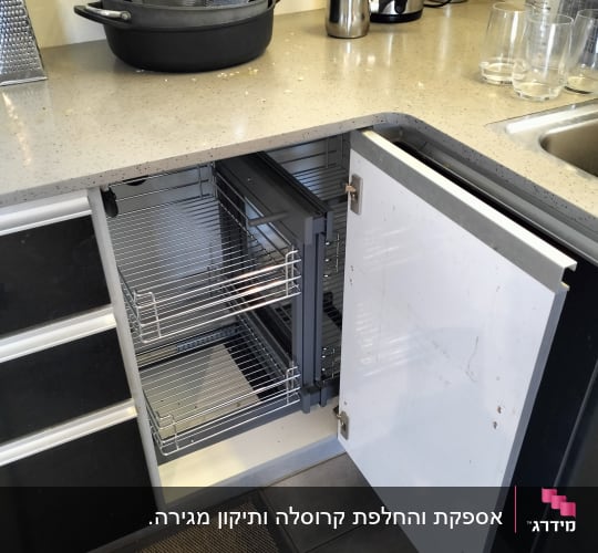 ארון מטבח פתוח עם מדפים נשלפים וסירים על השיש